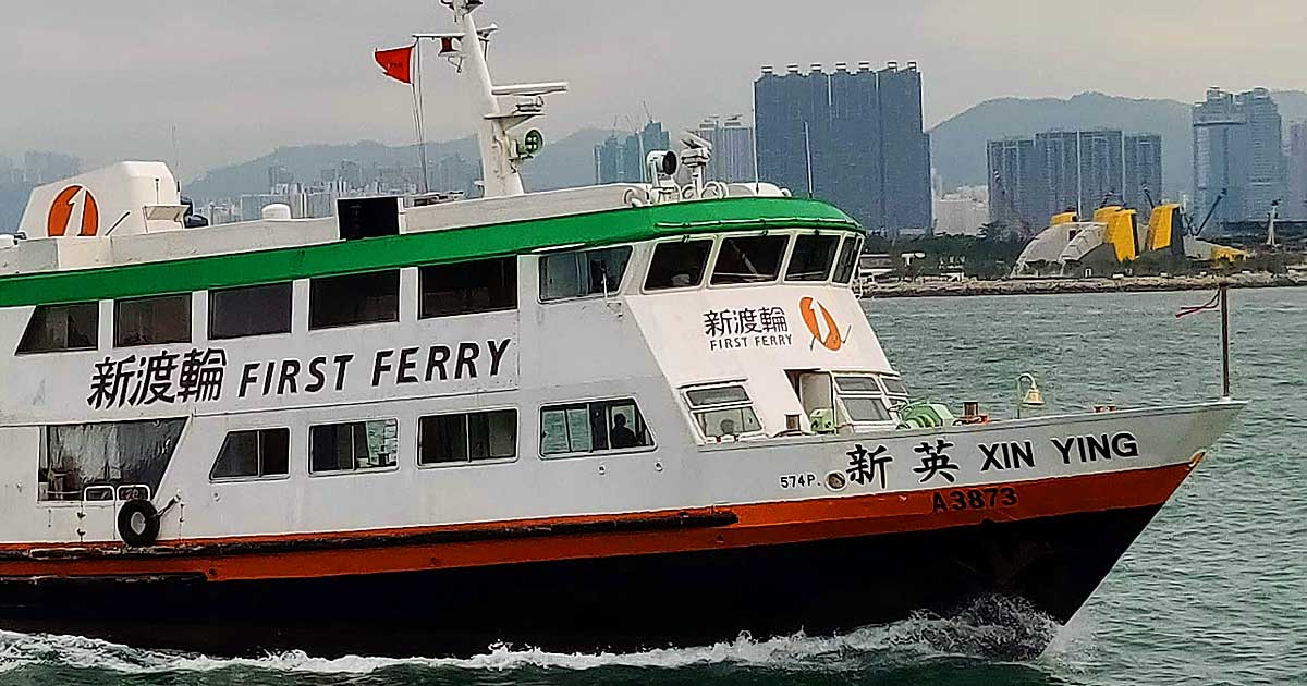First Ferry boat navigating Hong Kong harbor waters near Lantau Island, with urban skyline in the background